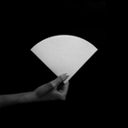 The Pull & Pour Shop Sibarist FAST medium cone coffee filter held by a hand against a black background.