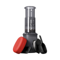 The Pull & Pour Shop AeroPress Go travel coffee maker with grey chamber, red filter case, scoop, and stirrer.
