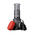 The Pull & Pour Shop AeroPress Go travel coffee maker with grey chamber, red filter case, scoop, and stirrer.