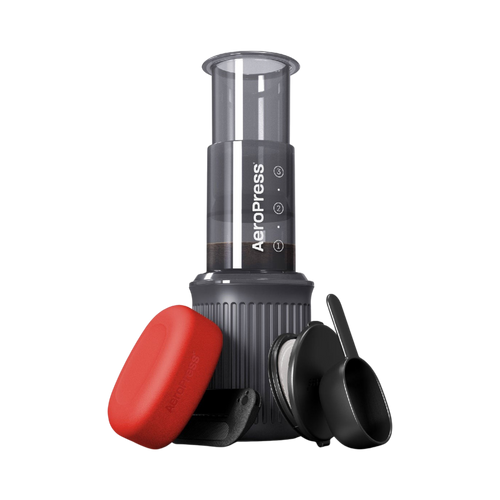 The Pull & Pour Shop AeroPress Go travel coffee maker with grey chamber, red filter case, scoop, and stirrer.