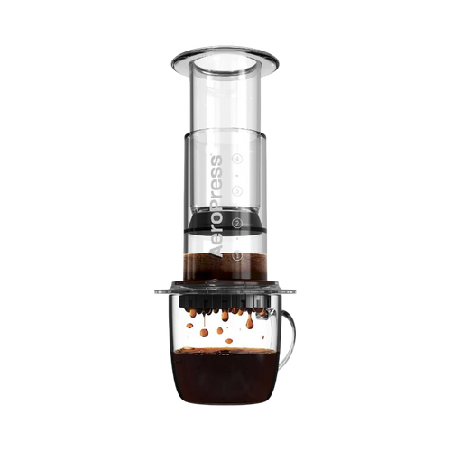 The Pull & Pour Shop AeroPress Clear coffee maker in transparent Tritan plastic brewing coffee into a glass mug.